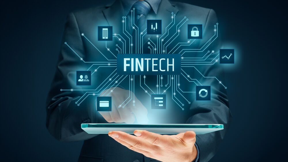 Close up of a professionally dressed man holding a slate over which fintech technologies over in virtual form